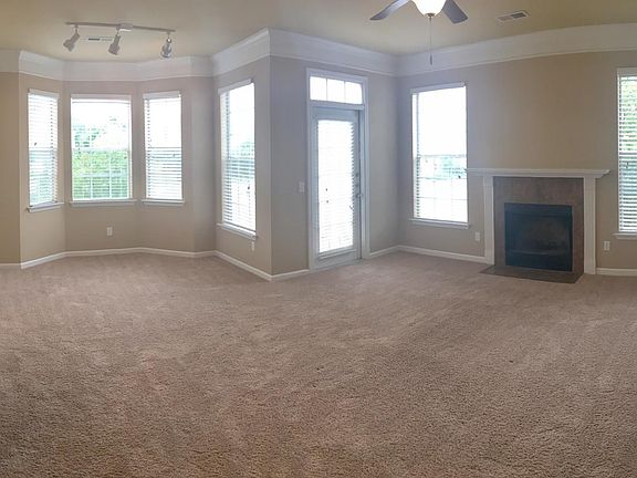 Triple crown molding, plush carpet, bay windows, and a fire place.