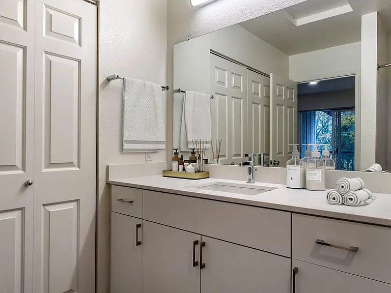Renovated Package I bath with cream quartz countertops, white cabinetry, and hard surface flooring