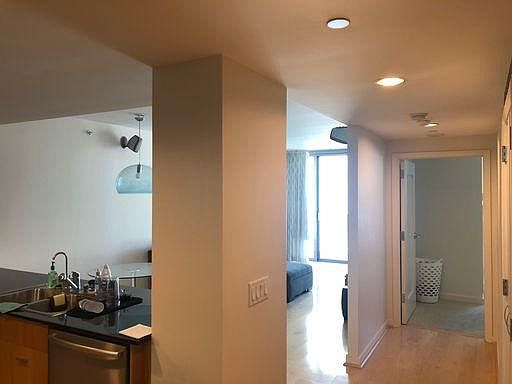 Another angle from the foyer. To the right in the foyer, there is a large walk-in-closet with custom-built shelving. In the hallway, there is another closet with a washer and dryer. The bathroom is adjacent and the bedroom is located at the end of the hal