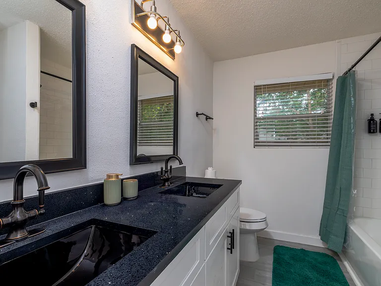 Full bathroom with double sinks and shower-tub combo attached to bedroom 1.