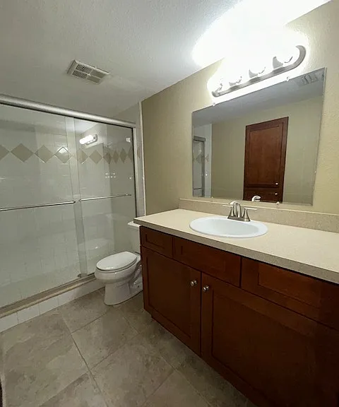 Bathroom has a large vanity plus a built in medicine cabinet and a glass enclosed shower.