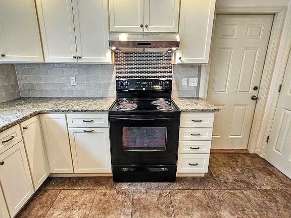 Kitchen stove, cabinets, and door to garage