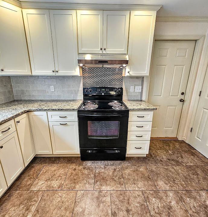 Kitchen stove, cabinets, and door to garage