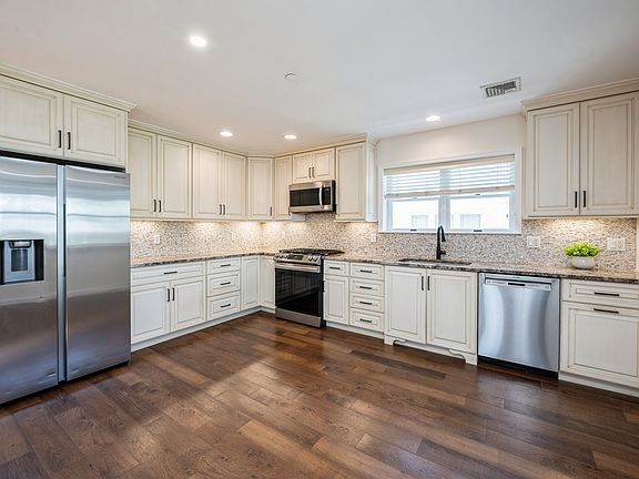 Modern, open kitchen fully equipped with stainless steel appliances, plenty of quality cabinetry, quartz counters, recessed lights.