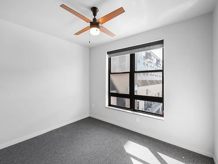 Bright and airy bedroom with large window and modern ceiling fan, offering a cozy and relaxing atmosphere. Bright and airy bedroom with large window and modern ceiling fan, offering a cozy and relaxing atmosphere.