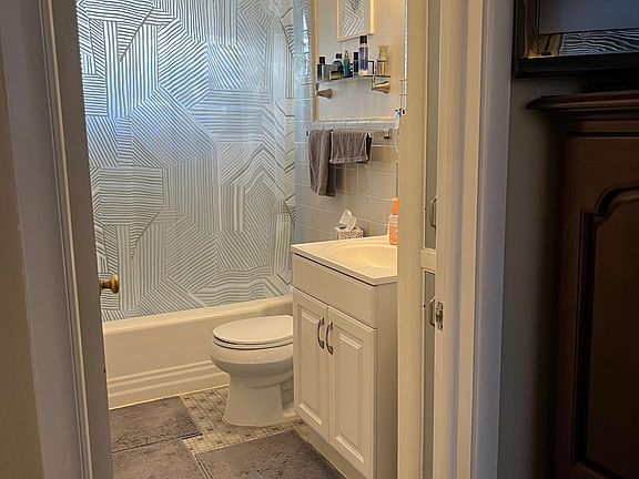 bathroom tub/shower, toilet, lavatory sink and vanity, medicine chest/mirror, and small built-in linen closet.
