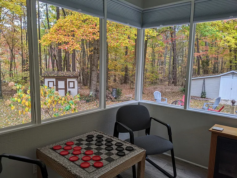 Inside sunroom looking out at the playhouse and fire ring area.