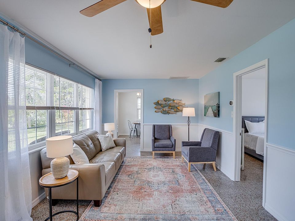 Furnished spacious living room with large picture windows, terrazzo floor and ceiling fan