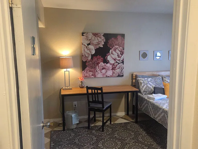 Furnished bedroom with a dedicated desk workspace, bedside lighting, and soft carpeting for added comfort.