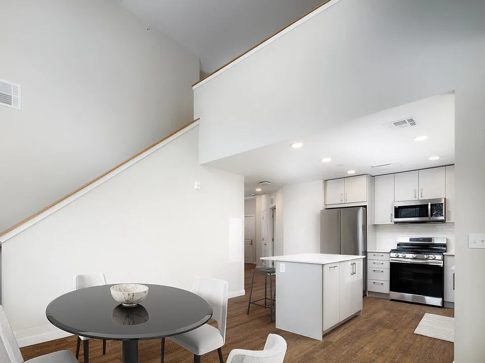 Loft apartment with stainless steel appliances, white quartz countertops, light grey cabinetry, and hard surface flooring