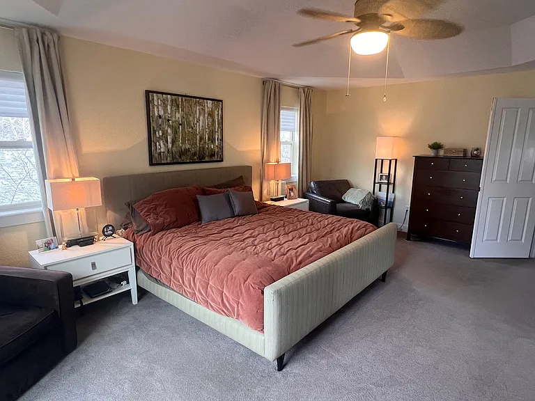 Main suite with ceiling fan, sliders to balcony on the left.