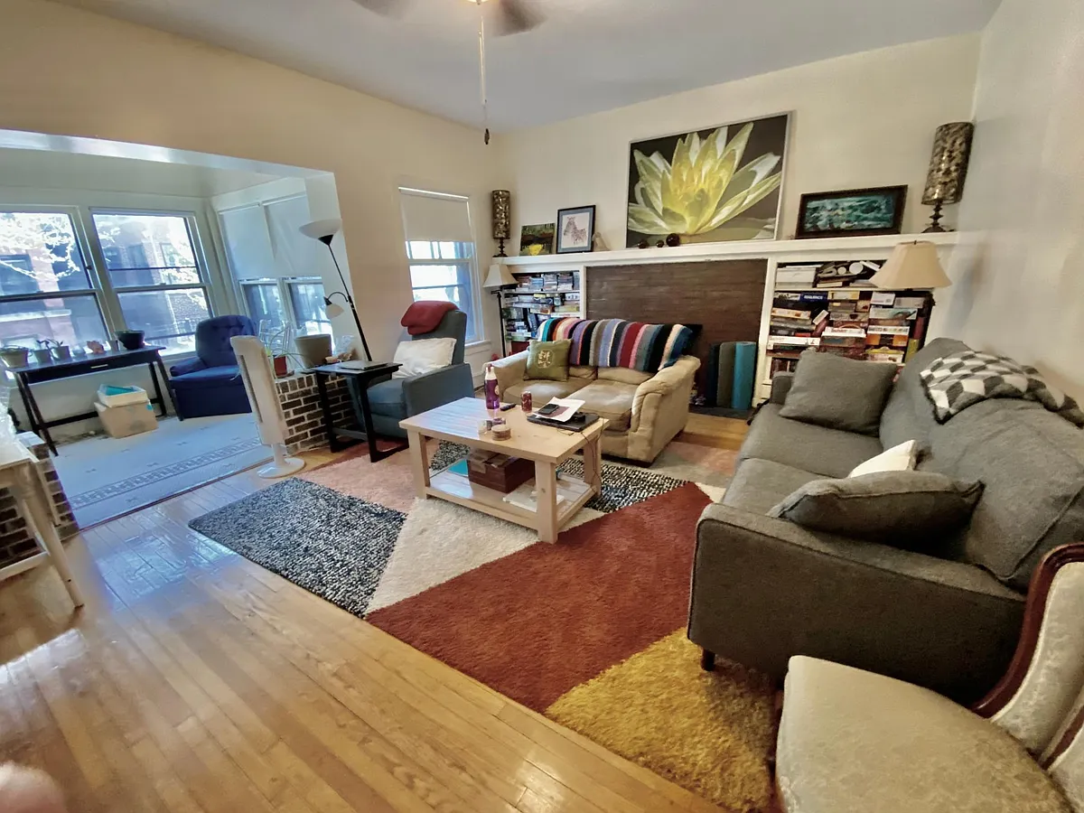 Expansive Living Room with decorative fireplace opens to sunparlor and view of tree-lined street - 920 W Margate Ter #1W