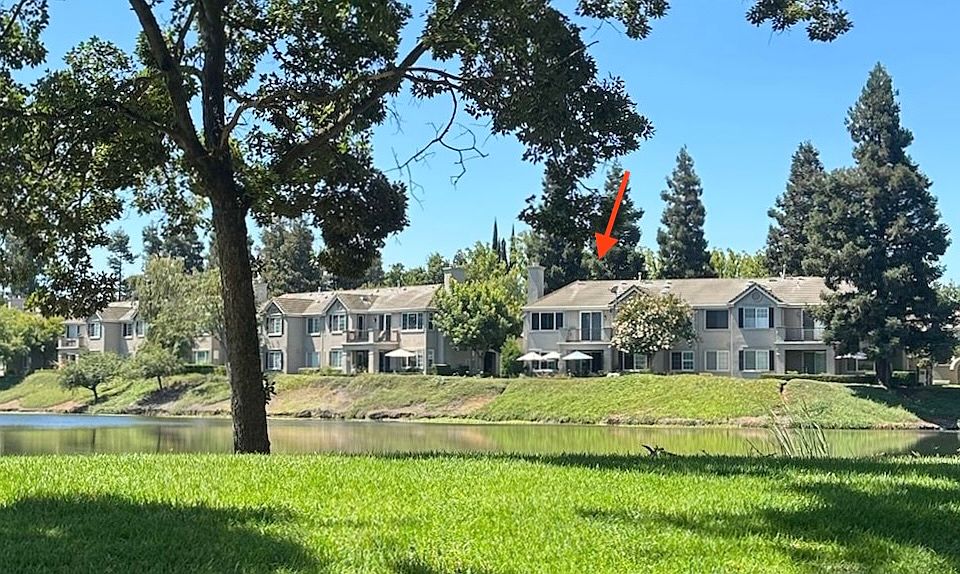 View of the listing from across Teal Lake. Gaze upon your future home from across the serene waters of Teal Lake! This stunning condo, marked by the arrow, offers an idyllic retreat within the exclusive Brookside community.