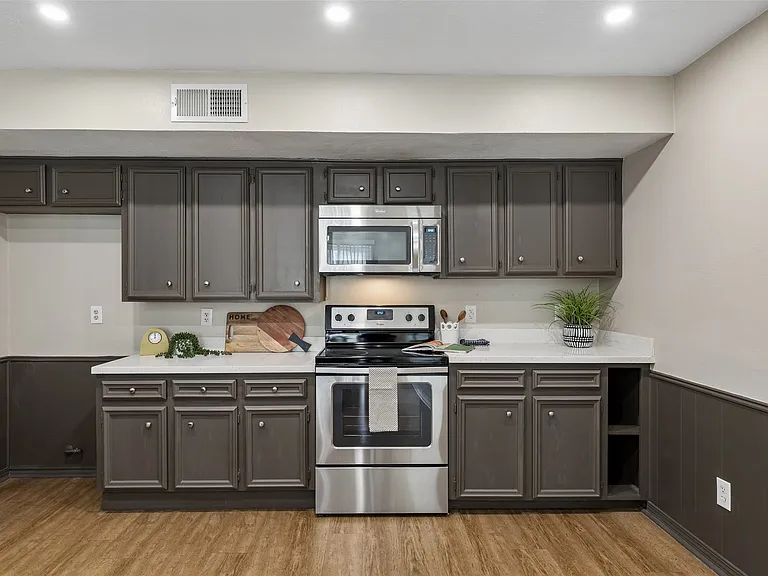 Kitchen featuring wood-finish flooring, dark cabinetry, light countertops, stainless steel appliances, and recessed lighting
