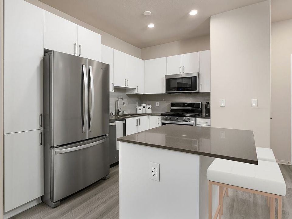 Renovated Package I kitchen with quartz countertops, white cabinetry, stainless steel appliances, hard surface vinyl plank flooring, and tile backsplash