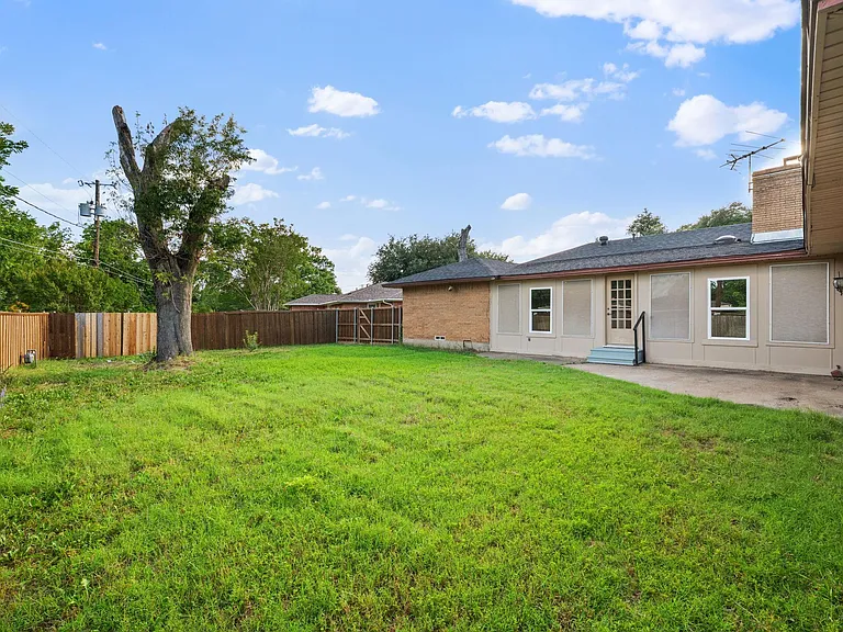 Fenced backyard with a grassy lawn and patio area, offering easy outdoor space for relaxing or entertaining.