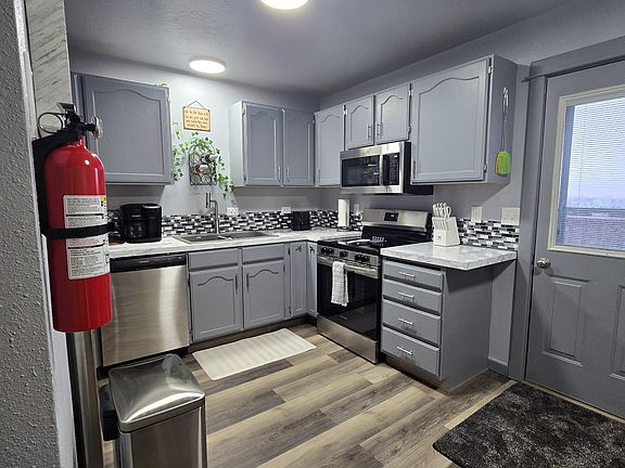 Exit kitchen door to large raised back deck that overlooks the city and features a smoker/grill and patio furniture.