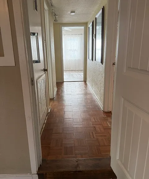 hallway features parquet wood flooring, a/c closet, bath, and bedroom access