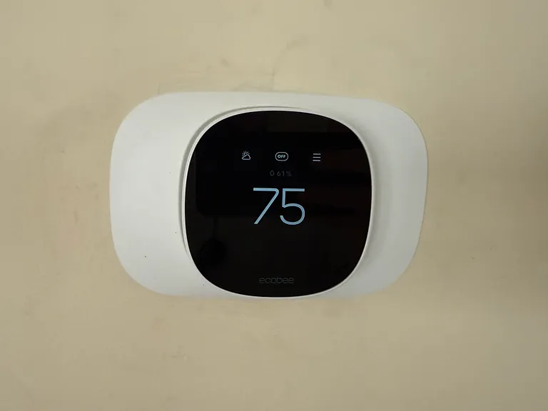 An Ecobee smart thermostat is installed in the living room. Smart temp settings can lower heating costs. Can monitor and control heating from your phone (ie: turn down the heat if you go on vacation; turn it back up a few hours before you arrive home).