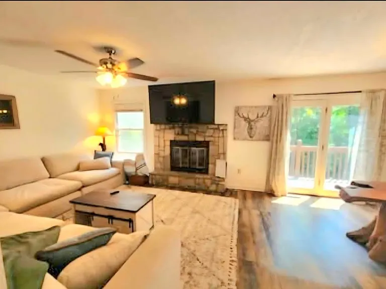 Large open living room/ kitchen/dining area with fireplace and sliding doors to deck.