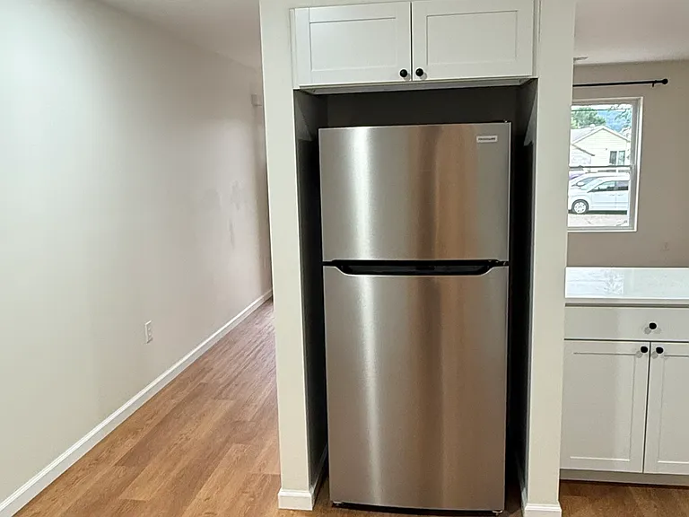 Brand-new kitchen featuring Whirlpool stainless-steel appliances, including range and built-in microwave, modern white cabinetry with ample storage, quartz-style countertops, subway-tile backsplash, and attractive new flooring.