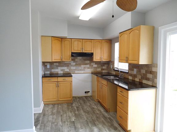 Kitchen with maple cabinets and new black appliances.