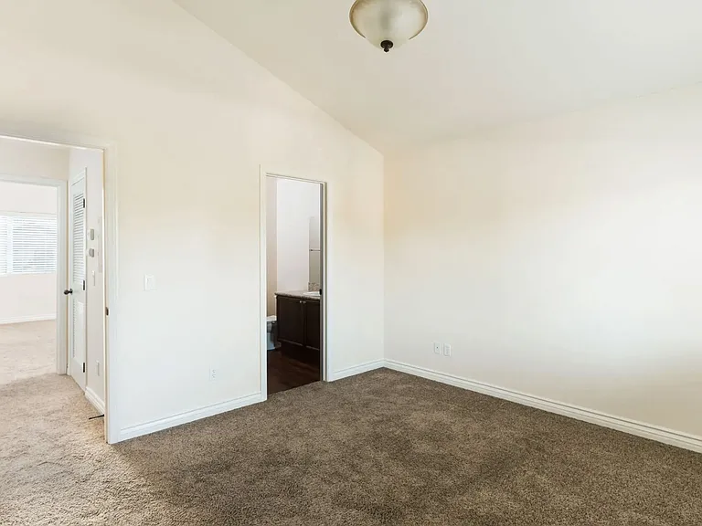 Large carpeted bedrooms with shared bathroom and cathedral ceilings at The Nines Townhomes in Escondido, California.