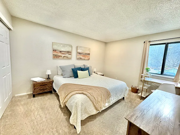 Bedroom angle from the door with smart TV on the wall above the credenza and large closet with matching night stands and lamps on either side