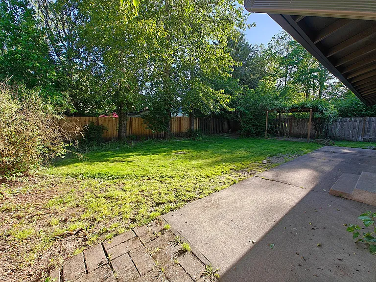 Large shaded fenced backyard with patio and pergola.