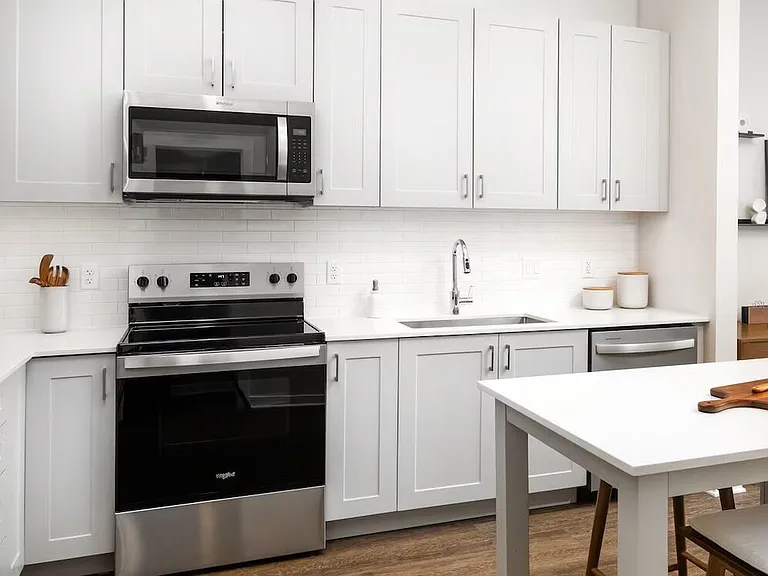 Design Collection II kitchen with stainless steel appliances, grey cabinetry, white tile backsplash, white quartz countertops, and hard surface flooring (Representative photo)