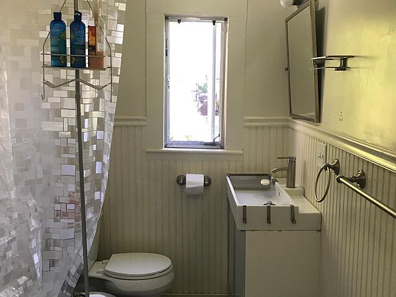 Upgraded bathroom with penny tiles, wainscoting and claw foot tub.