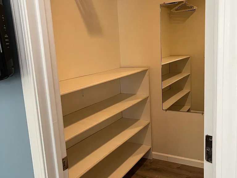 Walk-in Closet with bars and and a shelf on the opposite side of this, as well as a big mirror inside the closet