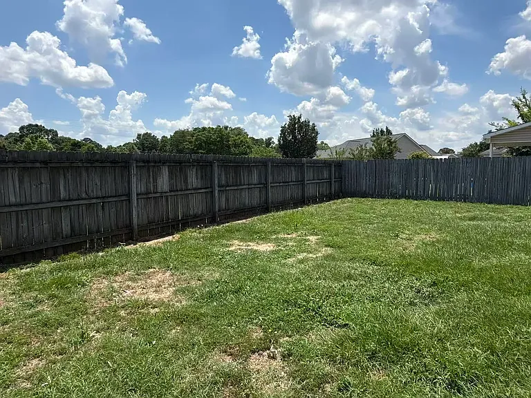 Fully enclosed backyard bordered by a secure privacy fence, offering an ideal space for outdoor activities.