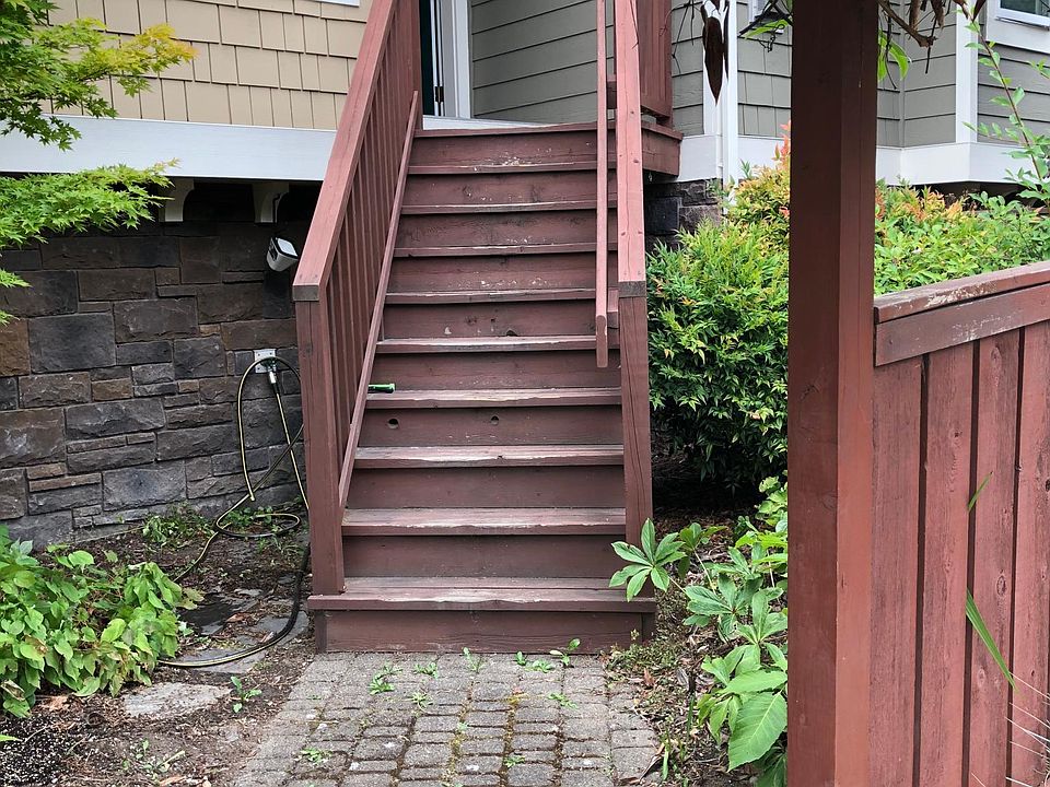 Entry to the townhouse via the front yard. The front entry door is on top of the wooden stairs, on the second floor