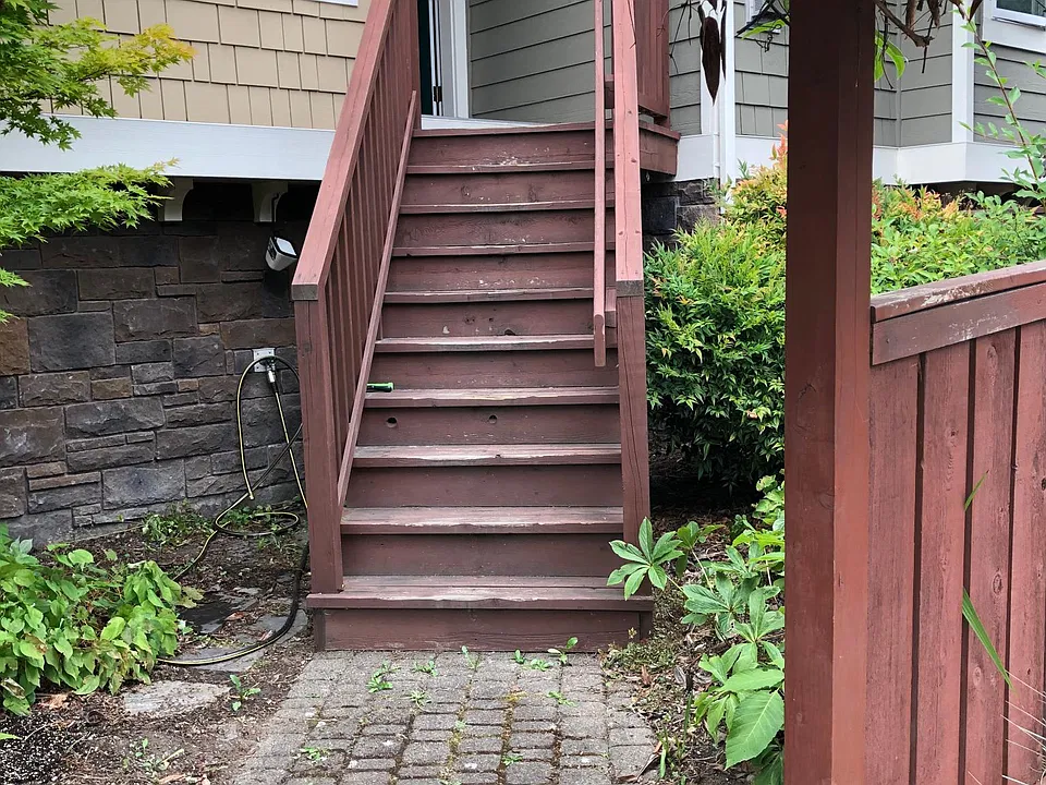 Entry to the townhouse via the front yard. The front entry door is on top of the wooden stairs, on the second floor