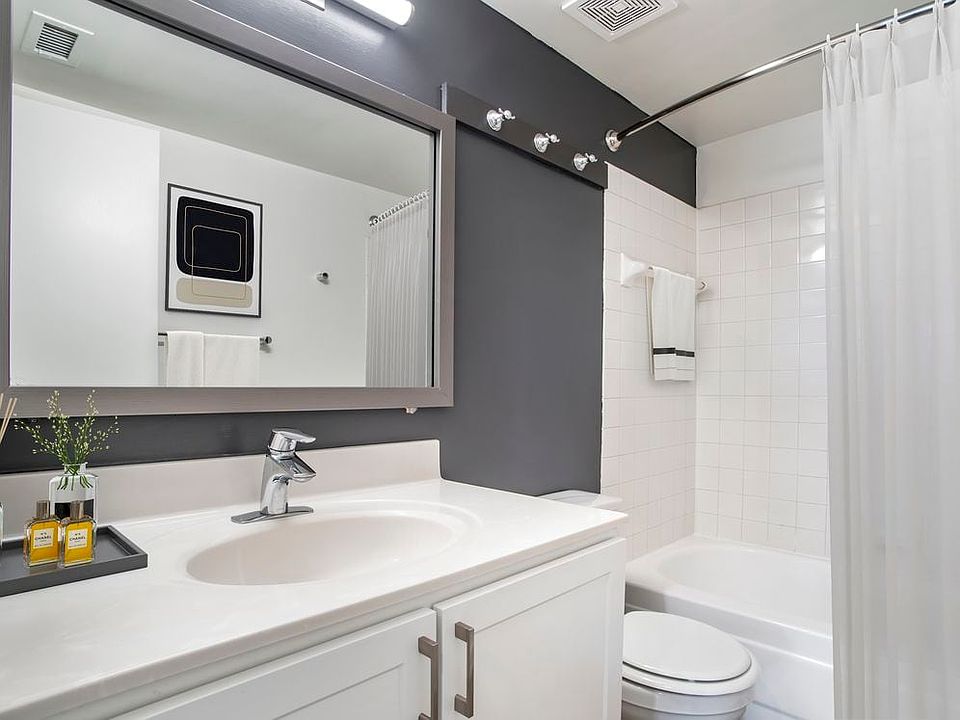 Renovated Package II bath with white countertops and cabinetry, accent wall, and hard surface flooring