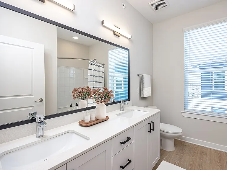 Townhome primary bath with dual sink vanity, quartz countertops, and hard-surface vinyl plank flooring
