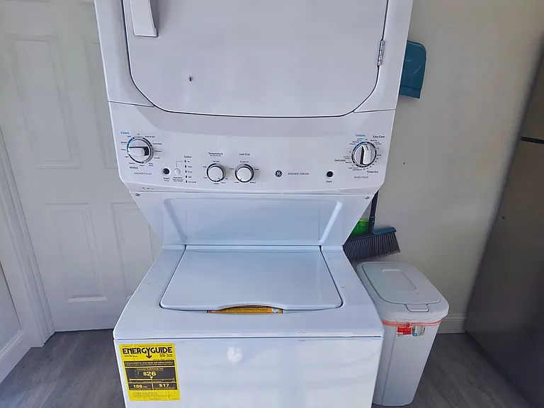 Laundry space with washer, cleaning tools, and trash bin