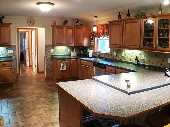 Remodeled kitchen features: tile floors, maple cabinets, tile back splash, stainless appliances, peninsula breakfast bar, custom lighting.