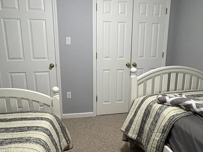Furnished bedroom with two twin beds, carpeted floors, and a double-door closet for convenient storage.