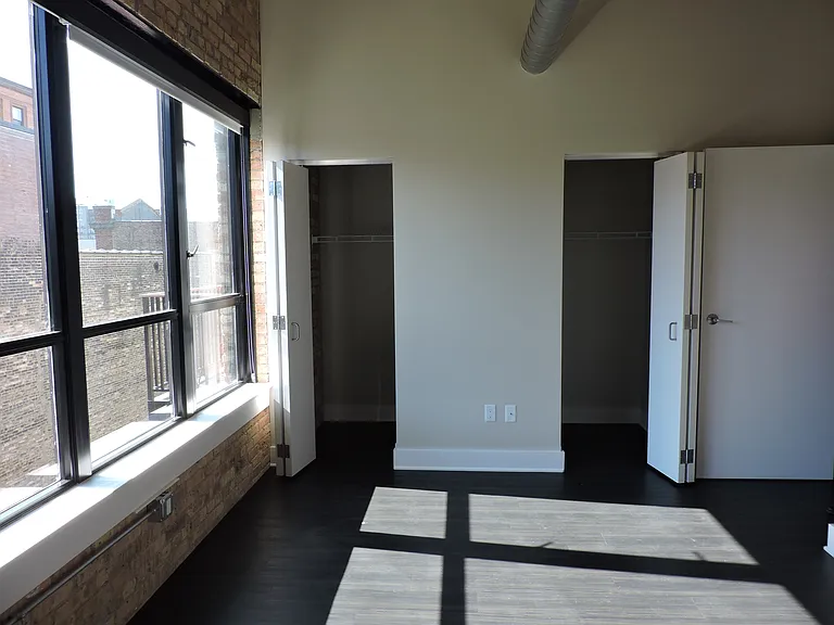 Primary Bedroom of #203 - Windows are South Facing. Loft style partition wall located to the right in this photo. Open air gap above walls of bedrooms, not fully enclosed.