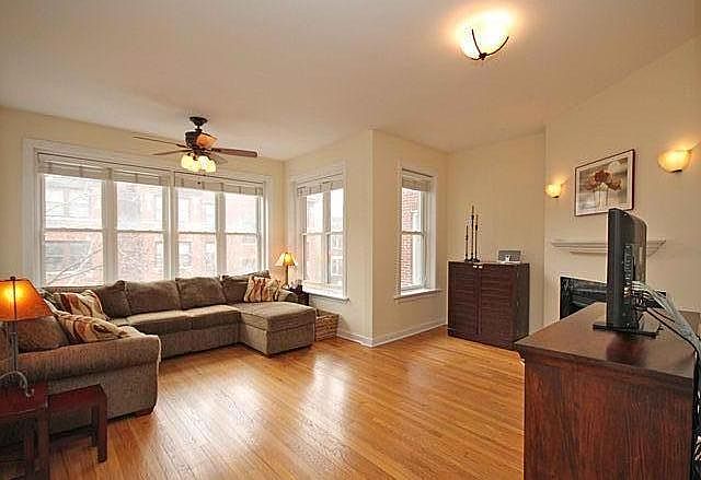 Living room. Lots of sunlight with large windows and white wood blinds.