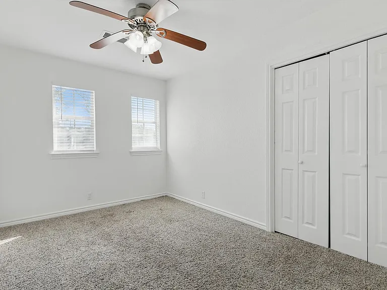 Unfurnished bedroom featuring carpet, a closet, baseboards, and a ceiling fan