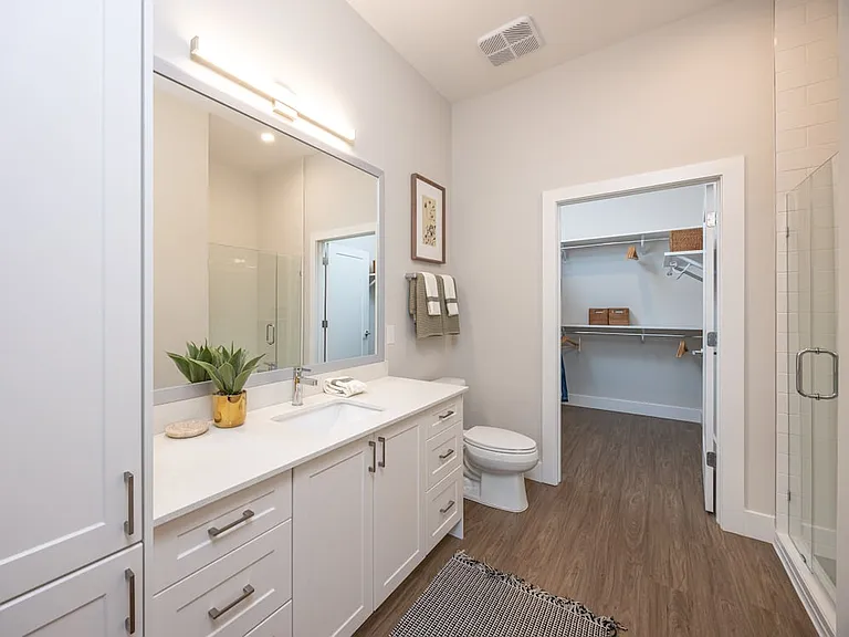 Primary bath with white quartz countertop, white cabinetry, and hard surface vinyl plank flooring