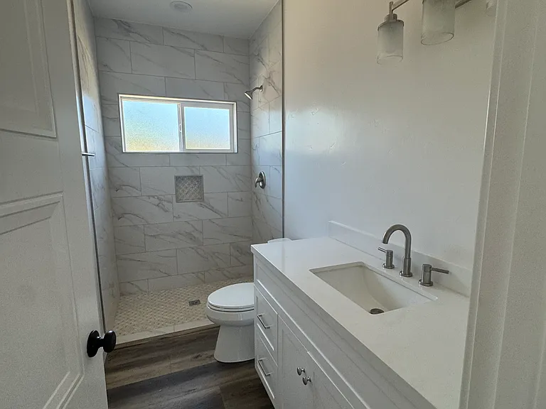 Hallway restroom is located between bedroom 1 and bedroom 2 with whisper quiet combo fan/light and fully-tiled walk in shower.