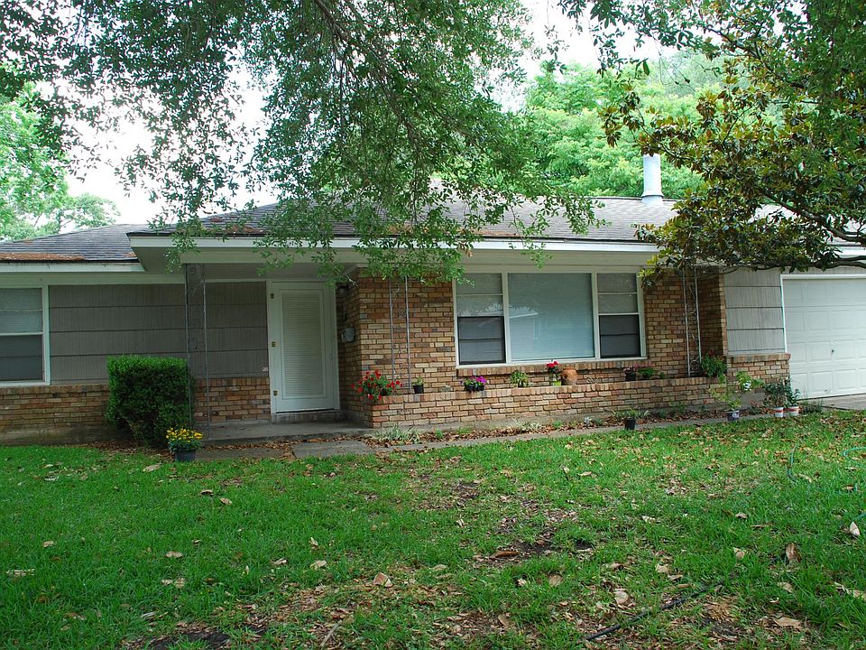 Front yard with a two-car garage on the right side. Magnolia tree is off to the right and large live oak tree is off to the left in this picture.