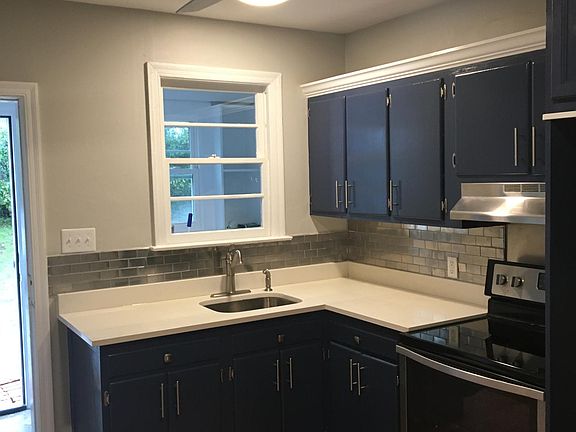 Note the crown molding above cabinets, the stainless steel tile backsplash, white quartz counters, the stainless steel ceiling fan