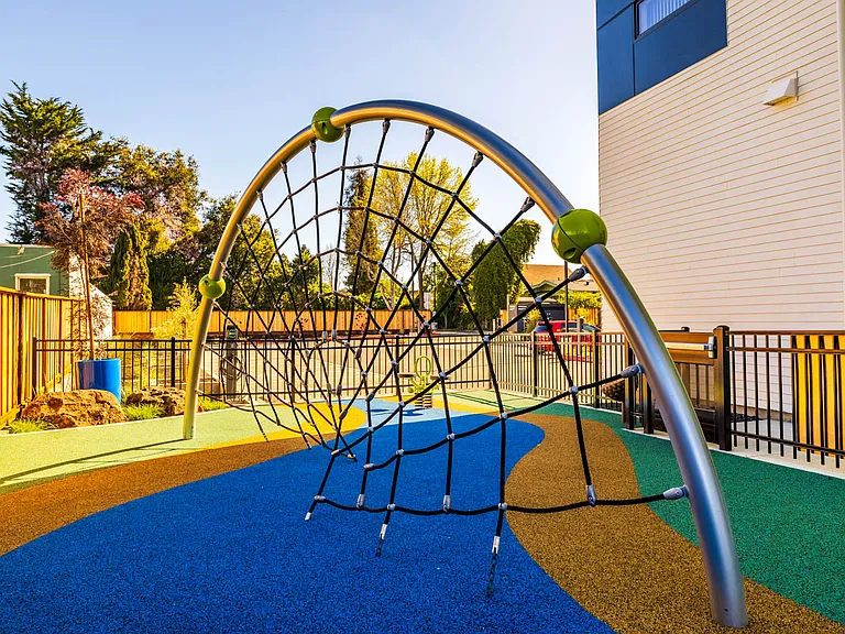 Dynamic outdoor play area features a modern climbing structure.