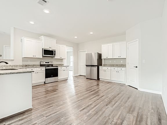 Upgraded kitchen with crown molding on the white cabinets and wood-style flooring throughout.