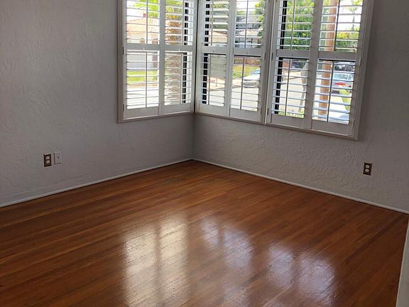 Living room -- double windows face north; single window faces west. New window shutters and ceiling fan. Hardwood floor.